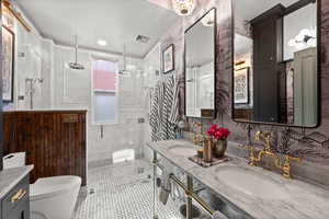 Full bathroom with toilet, a stall shower, and double vanity