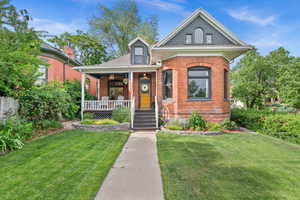View of front of property featuring a porch, a front yard, and brick siding