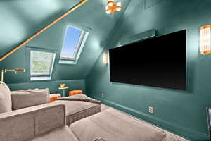Home theater with vaulted ceiling, a skylight, and baseboards