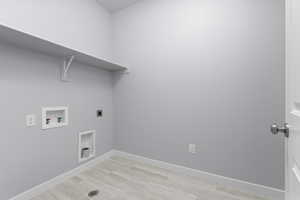 Washroom featuring light wood-type flooring, hookup for an electric dryer, washer hookup, and baseboards