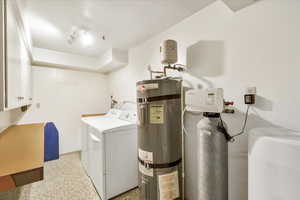 Laundry room with washer and dryer, water heater, cabinet space, and baseboards
