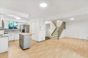 Kitchen featuring white appliances, wooden counters, a center island, and light wood-type flooring
