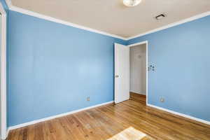 Unfurnished room featuring baseboards, wood finished floors, and crown molding