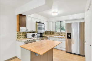 Kitchen featuring stainless steel appliances, butcher block counters, and tasteful backsplash