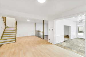Unfurnished room with ceiling fan, stairway, and wood finished floors