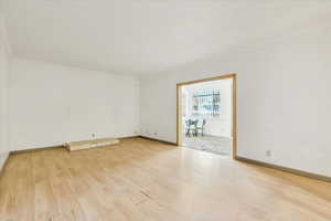 Spare room featuring ornamental molding, wood finished floors, and baseboards