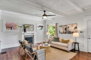 Living area with a textured ceiling, a fireplace with flush hearth, beamed ceiling, hardwood / wood-style floors, and baseboards