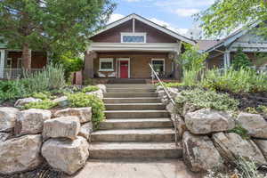 View of front of house with a porch, brick siding, and stairway