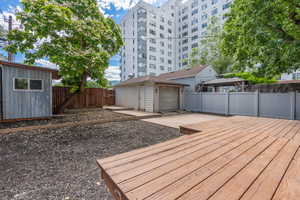 Wooden terrace featuring a fenced backyard, an outbuilding, a garage, and a gazebo