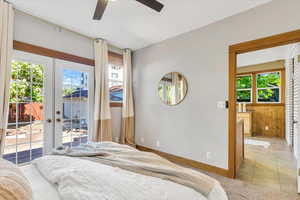 Bedroom featuring access to outside, french doors, multiple windows, wooden walls, and baseboards