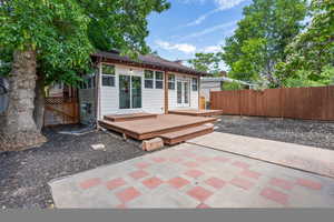 Back of property with a deck, a fenced backyard, french doors, and a patio