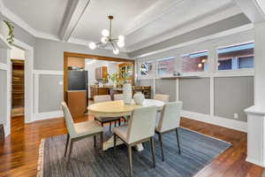 Dining space with a chandelier, a textured ceiling, wood finished floors, and beamed ceiling