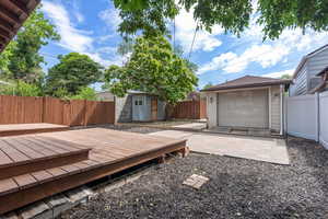 Wooden deck with an outdoor structure and a fenced backyard