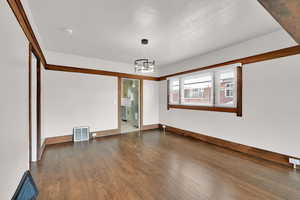 Spare room featuring wood finished floors, a chandelier, and baseboards