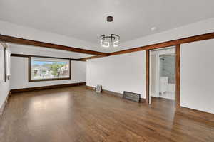Spare room featuring a chandelier, wood finished floors, baseboards, and a smoke detector
