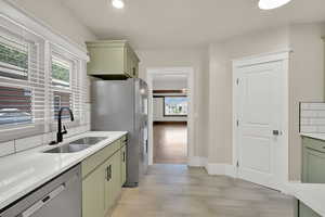 Kitchen with green cabinets, appliances with stainless steel finishes, a sink, and plenty of natural light