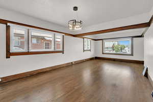Unfurnished room featuring wood finished floors, a chandelier, and baseboards