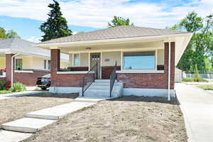 Bungalow featuring brick siding, a porch, and a shingled roof