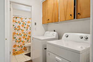 Laundry area with washer and dryer, tile patterned floors, and cabinet space