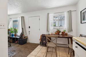 Entryway with plenty of natural light, a baseboard heating unit, light tile patterned floors, and a textured ceiling