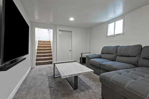 Carpeted living room with stairway and recessed lighting