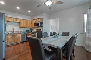 Dining area with dark wood-style floors, a ceiling fan, and recessed lighting