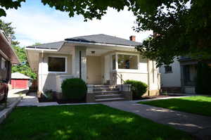 Bungalow-style house with a front yard, a chimney, and a shingled roof