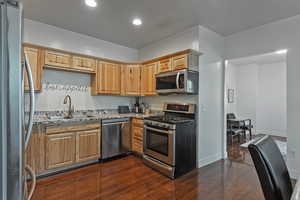 Kitchen featuring appliances with stainless steel finishes, dark wood-type flooring, recessed lighting, and light stone countertops