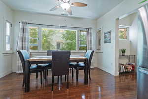Dining space featuring dark wood-type flooring and ceiling fan