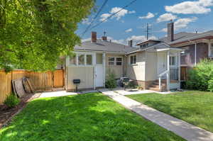 Rear view of property featuring a gate, a chimney, and roof with shingles
