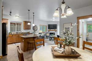 Dining room with light tile patterned flooring, a fireplace, and a chandelier