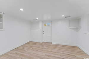 Basement with light wood finished floors, baseboards, and recessed lighting
