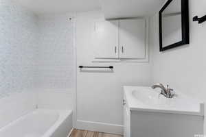 Bathroom featuring vanity, wood finished floors, baseboards, and shower / washtub combination