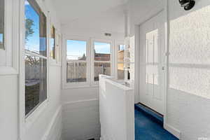 Unfurnished sunroom featuring vaulted ceiling and a textured wall