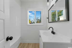 Bathroom with vanity, wood finished floors, and baseboards