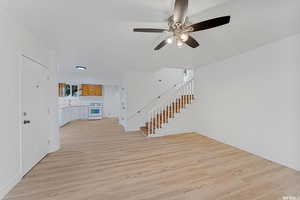 Entrance foyer featuring a ceiling fan, light wood-type flooring, stairs, and baseboards