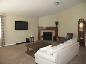 Living room with carpet flooring, a fireplace, and baseboards