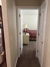Hallway featuring dark carpet