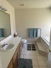 Bathroom featuring a bath, vanity, tile patterned floors, and toilet