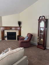 Living area with carpet flooring, baseboards, and a fireplace