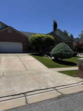View of front of property with a front yard, driveway, a garage, and brick siding