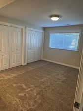 Unfurnished bedroom with multiple closets, carpet floors, and baseboards