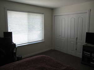 Bedroom with a closet, dark colored carpet, and an office area