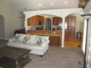Living room featuring arched walkways, recessed lighting, and light carpet