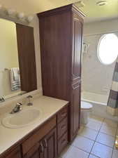 Bathroom with vanity, toilet, tile patterned floors, and shower / bath combo with shower curtain