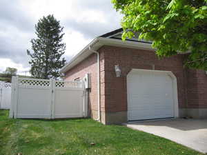 View of property exterior featuring brick siding, driveway, and a gate