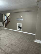 Basement featuring carpet, a textured ceiling, baseboards, and stairs