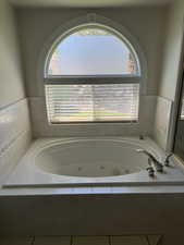 Full bathroom featuring healthy amount of natural light and a tub with jets