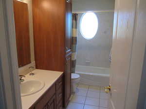 Bathroom featuring tile patterned floors, vanity, toilet, and shower / bath combo