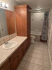 Bathroom featuring vanity, tile patterned floors, toilet, and shower / bath combo with shower curtain